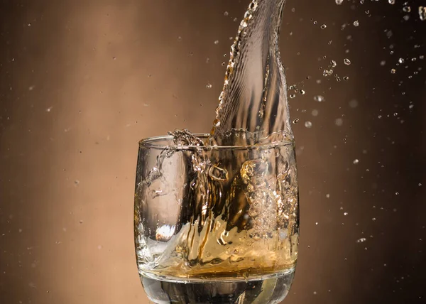 Fallendes Glas Mit Whiskey Und Spray Auf Braunem Hintergrund — Stockfoto