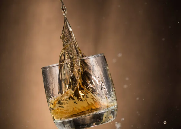 Vallend Glas Met Whiskey Spray Een Bruine Ondergrond — Stockfoto