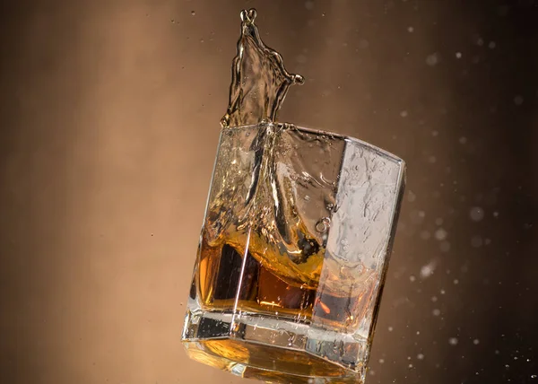 Falling Glass Whiskey Spray Brown Background — Stock Photo, Image