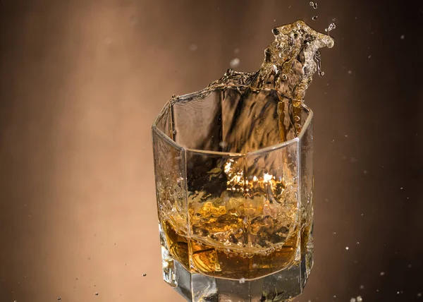 Vallend Glas Met Whiskey Spray Een Bruine Ondergrond — Stockfoto