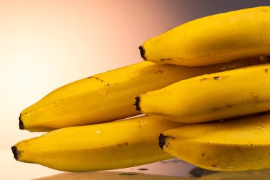 Sarı eğimli arka planda küçük olgun muzlar.