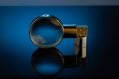 Bir büyüteç, metal bir çantada büyüteç ve karanlık bir arka planda dahili flaş bellek.