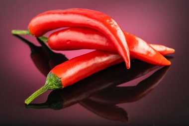 Kırmızı, uzun kırmızı biberler kırmızı, koyu bir arka planda alev alev yanıyor.