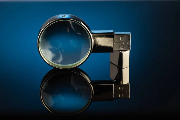 a magnifying glass, a magnifier in a metal case with a built-in flash drive on a dark background