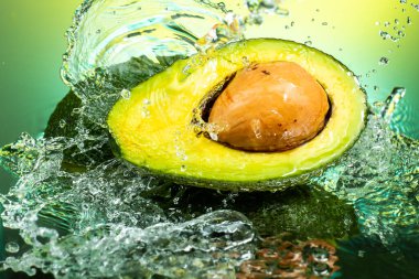 cut avocado in half with bone inside with splashing water on gradient background clipart