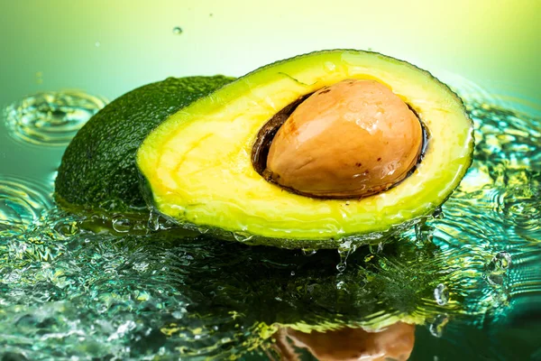Gesneden Avocado Tweeën Met Bot Binnen Met Spetterend Water Gradiënt — Stockfoto