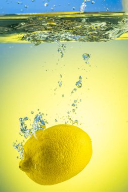 Tüm sarı limon eğimli arkaplanda sıçramalarla suyun altına düşüyor.