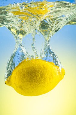 Tüm sarı limon eğimli arkaplanda sıçramalarla suyun altına düşüyor.