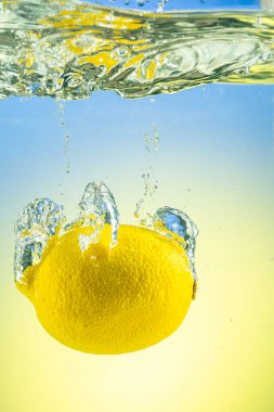 Tüm sarı limon eğimli arkaplanda sıçramalarla suyun altına düşüyor.