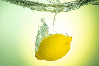 Tüm sarı limon eğimli arkaplanda sıçramalarla suyun altına düşüyor.