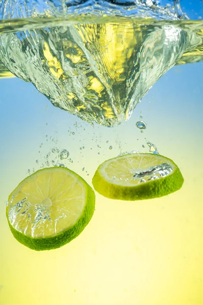 Green Lime Slices Falling Water Splashes Gradient Background — Stock Photo, Image