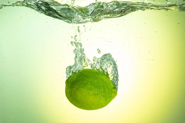 Целый Зеленый Лайм Падает Водой Брызгами Градиентном Фоне — стоковое фото