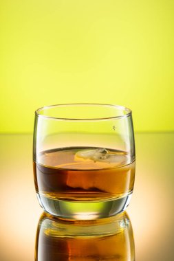 Renkli bir arka planda, buzlu viski bardağa sıçrar.