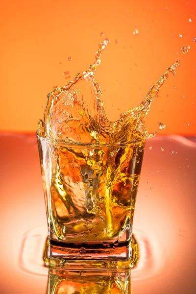 Whiskey Met Ijsplons Een Glas Een Gekleurde Achtergrond — Stockfoto