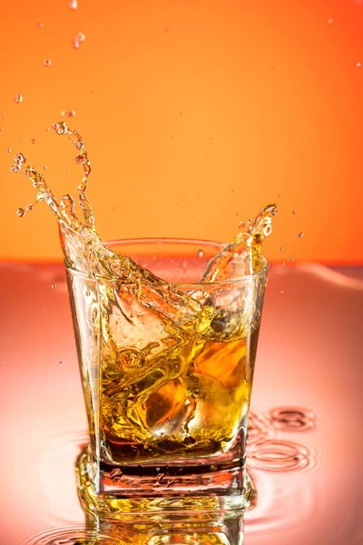 Whiskey Met Ijsplons Een Glas Een Gekleurde Achtergrond — Stockfoto