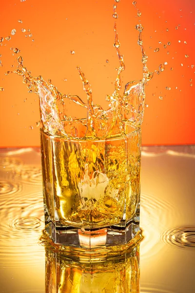 Whiskey Met Ijsplons Een Glas Een Gekleurde Achtergrond — Stockfoto