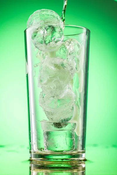 用绿色渐变背景的纯冰块把绿色的龙舌兰柠檬水倒入玻璃杯中 — 图库照片