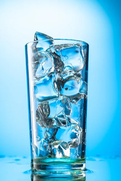 彩色梯度背景下玻璃杯中的纯冰块 方块是圆形的 — 图库照片