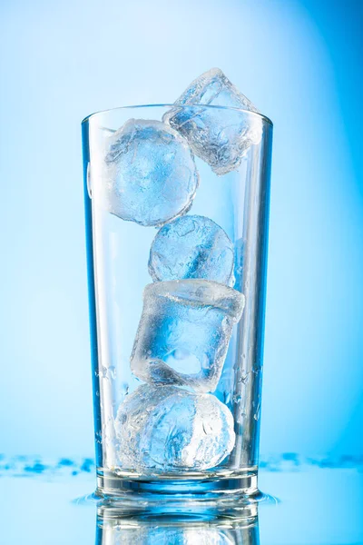 彩色梯度背景下玻璃杯中的纯冰块 方块是圆形的 — 图库照片