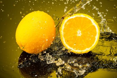 iki portakal, bir bütün ve yarıya bölünmüş siyah cam üzerinde damla ve su damlaları gradyan arkaplan ve yansıma