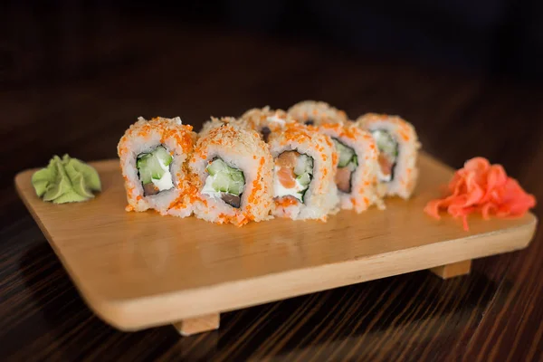 Japon yemekleri. Suşi uçan balık havyar ile alır. Zencefil ve wasabi ile ahşap bir gemide kaplı suşi.