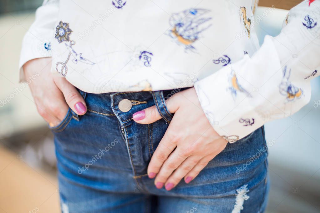 Young beautiful girl is holding her hand in a jeans patch. Close up.