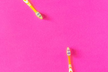 Parlak pembe bir arka plan üzerinde iki sarı ve turuncu diş fırçaları kapatın. Uzay kopyalayın. Diş fırçaları parlak sarı ve turuncu.