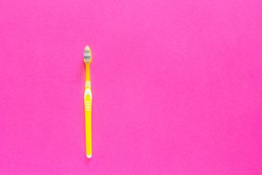 Parlak pembe bir arka plan üzerinde sarı diş fırçası kapatın. Diş fırçası arka sol tarafında yer alır. Kopya alanı.