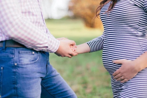 Будущие родители гуляют по парку. Муж держит жену за руку — стоковое фото