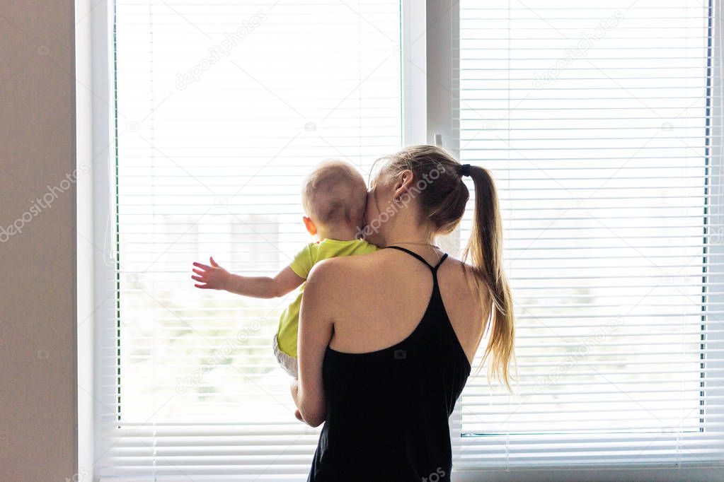 Mom holds the baby and looks out the window