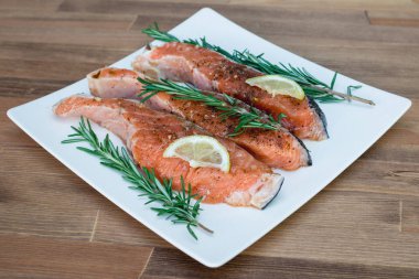 Beyaz plaka ve biberiye taze çiğ kırmızı balık fileto. yakın çekim