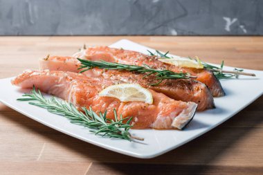 Beyaz plaka ve biberiye taze çiğ kırmızı balık fileto. yakın çekim