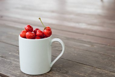 Kiraz güzel beyaz fincan kahverengi ahşap kaba kırsal tablo. Yaz rustik bahçe manzaralı. Kare, seçici odak. Yakın çekim