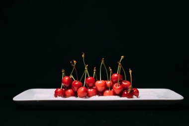 Taze kiraz ahşap mavi zemin üzerine plaka üzerinde. taze olgun kiraz. tatlı kiraz. Yakın çekim