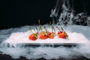 Kiraz ve çilek siyah bir zemin üzerine lezzetli taze çilek. yakın çekim