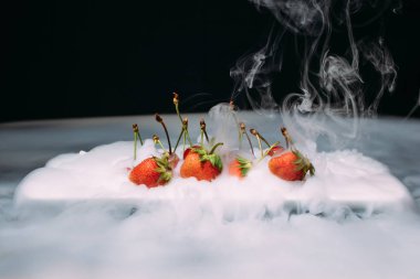 Kiraz ve çilek siyah bir zemin üzerine lezzetli taze çilek. yakın çekim