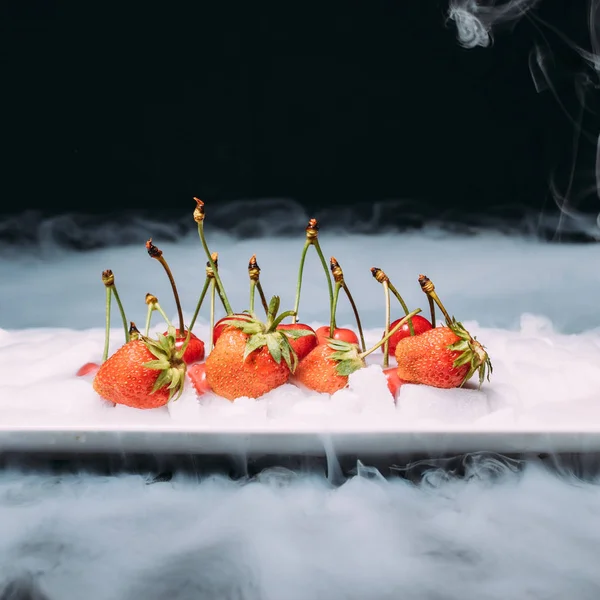 Kiraz ve çilek siyah bir zemin üzerine lezzetli taze çilek. yakın çekim