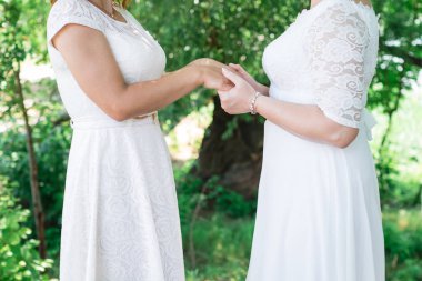 İki gelin hakkında bir şeyler fısıldayan ve gülüyor. Gelinlik güzel narin kız. Yakın çekim, metin kopyalama