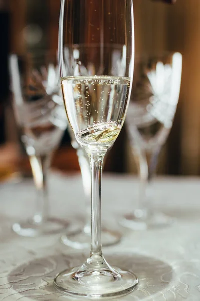 A glass of champagne and wedding rings. — Stock Photo, Image