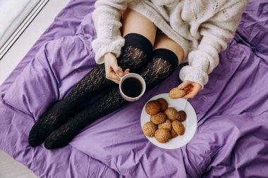 çay kahve içme ve pencerenin yanında otururken kurabiye yemek genç esmer kadın 