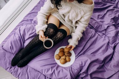 çay kahve içme ve pencerenin yanında otururken kurabiye yemek genç esmer kadın 