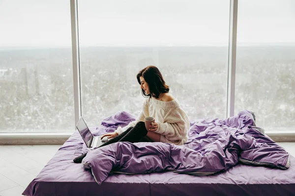 Joven Morena Mujer Bebiendo Café Usando Portátil Blanco Sentado Cama — Foto de Stock