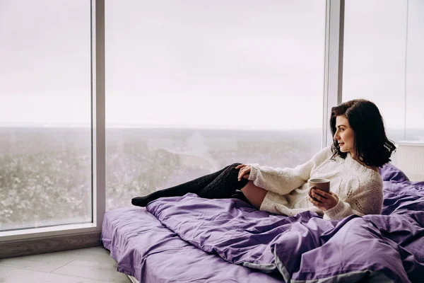 年轻的黑发女人喝茶在早上 而坐在附近的窗口 — 图库照片