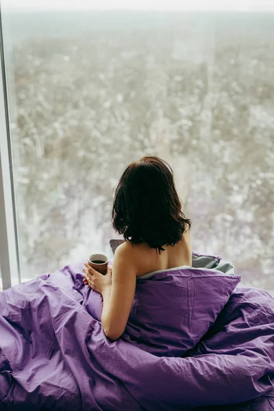 年轻的黑发女人喝茶在早上 而坐在附近的窗口 — 图库照片