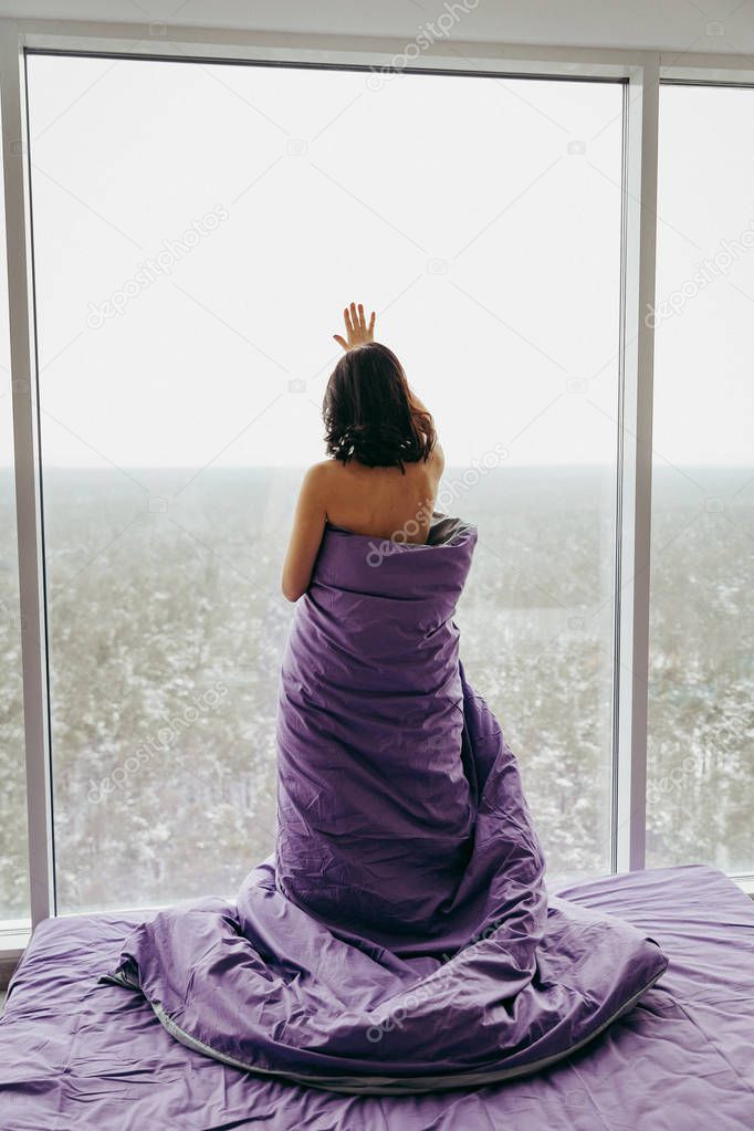 young brunette woman waking up next to the window 