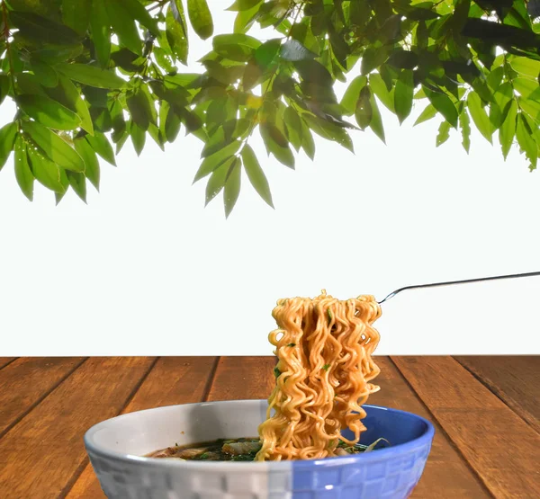 Anlık erişte çatal tarafından gösterdi. Bolw ahşap masa yanında teras üzerindedir. Resmin üst kısmında güneş tarafından tuttu yaprakları vardır.