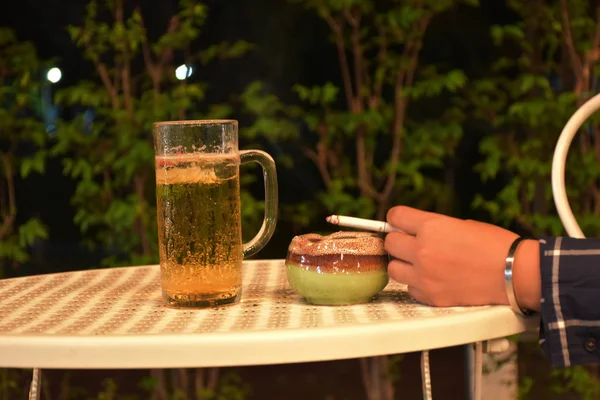 Bir sigara ile genç bir kadının eli ve bir kül atma