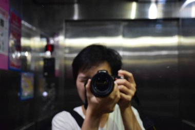 Bulanık bir fotoğrafçı kendini aynada asansörde alıyor.