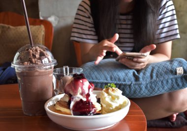 Kafe, tatlılar ve içki masasında. Arka plan Akıllı telefon kullanan bir kız bulanık.