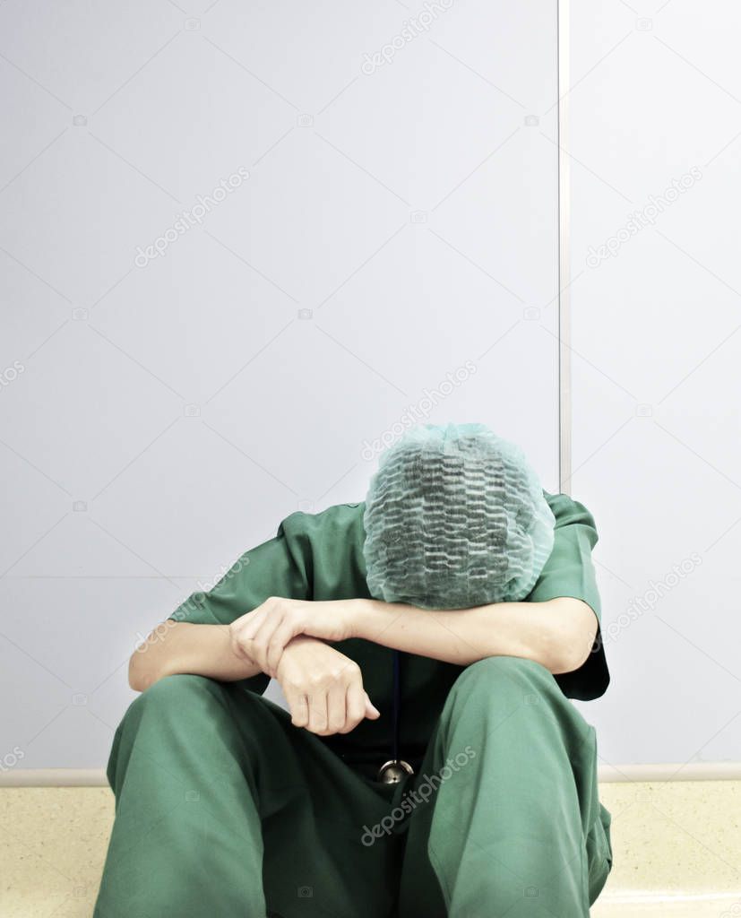 A tried nurse is sitting on the floor.  Blurred is applied.